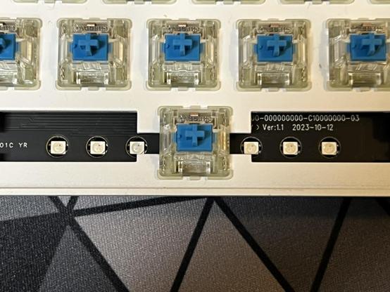 A closeup of the PCB area underneath the spacebar. Either side of the blue switch are three unlit LEDs.