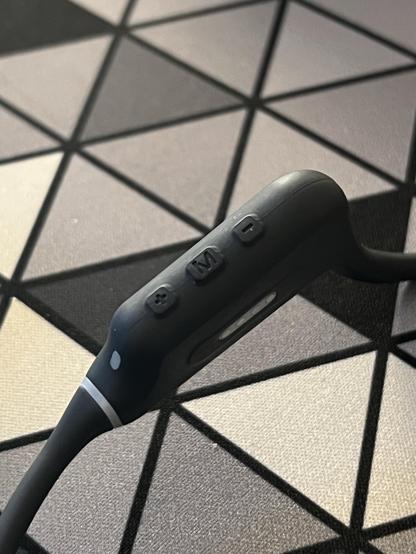 A closeup of the controls side of some bone conduction headphones showing three water sealed push buttons in a line.