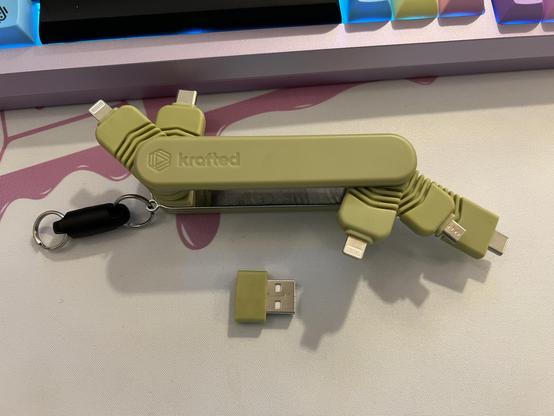 A pen knife like USB multi adapter with five connectors spread out. Two at one end, three at the other. A USB A to C adapter sits to one side.