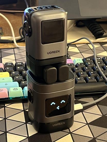 A USB C wall charger stacked on top of a wireless desktop charger. It has its cover on so it looks like a little sitting robot.