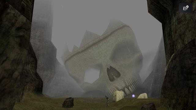 A huge skull resting in a canyon and shrouded in fog. It’s a videogame screenshot with very low detail geometry and textures.