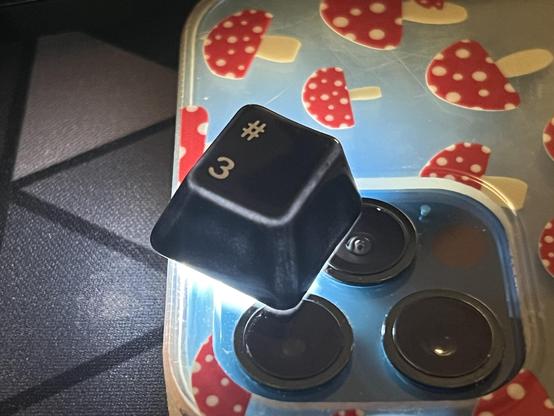 A ceramic keycap lit from beneath with a bright white light. Light is showing through the top edges, though the side glazing seems to be thicker here with only a little glow through.