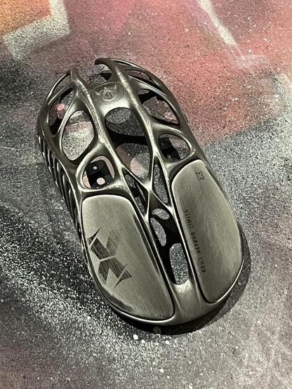 The skeletal metal outer shell of a gaming mouse roughed up with sandpaper.