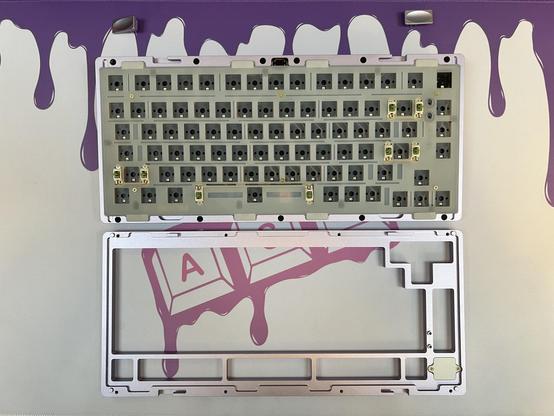 A barebones mechanical keyboard with the top shell removed and set beside it.