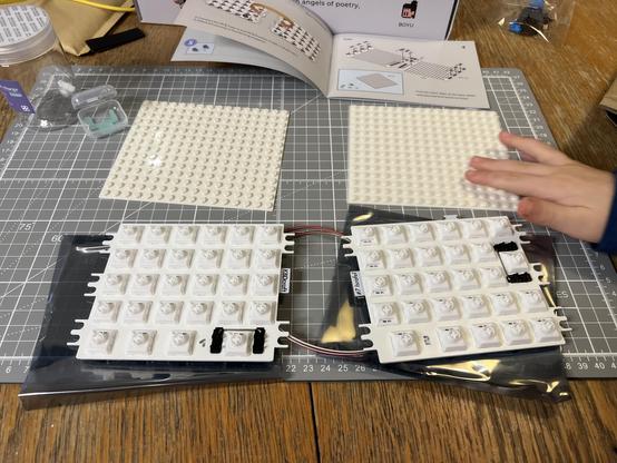 Two fully populated split keyboard PCBs sat in front of two similarly sized off-white not-actually-LEGO baseplates.