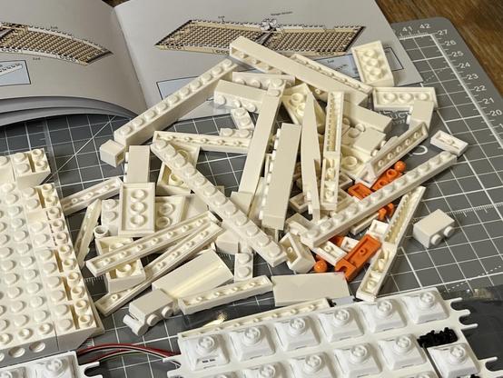 A chaotic pile of bricks, piled between an instruction manual and a keyboard PCB with installed switches.