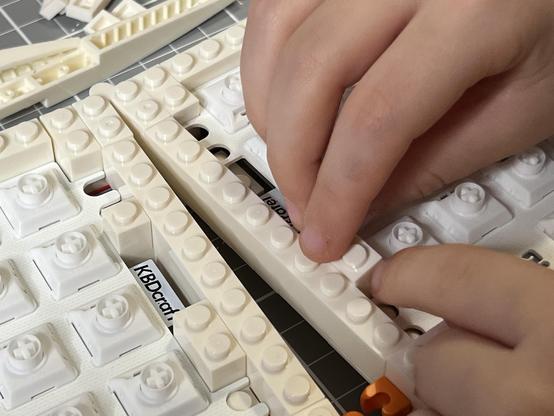 A brick being placed my small hands into one of the keyboard halves.