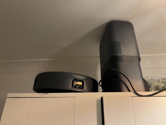 A robot vacuum cleaner and base station sat on top of a wardrobe.
