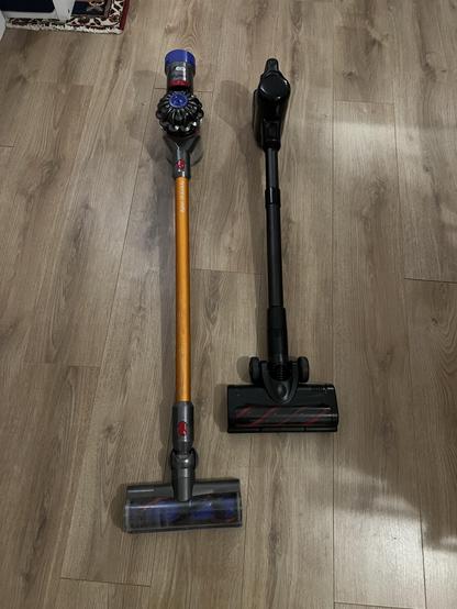 A Dyson cordless vacuum next to the Eufy E20 cordless vacuum.