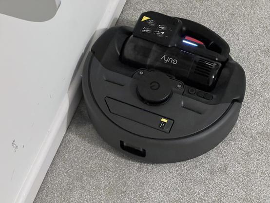 A robot vacuum cleaner with a very large and obvious cordless vacuum bulging out of it.