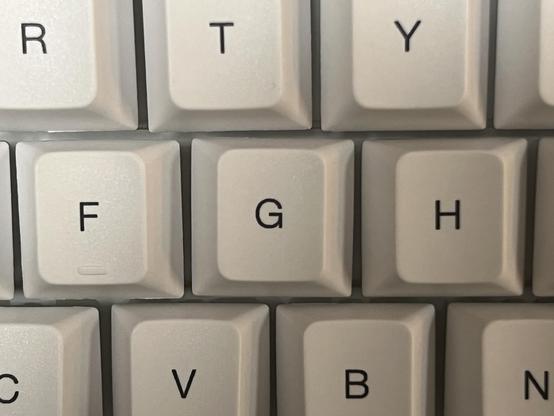 A closeup of the F, G and H keys on a mechanical keyboard. The G is twisted noticeably clockwise and most of the other keycaps are out of alignment too.