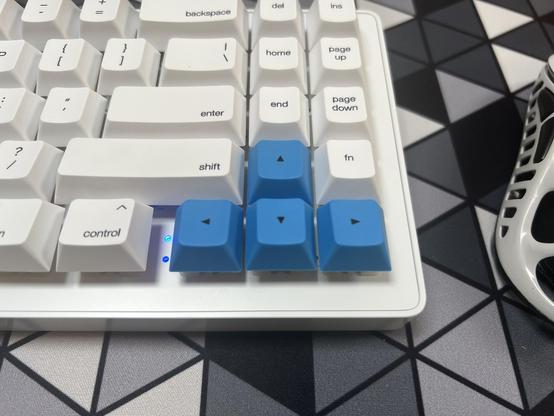 A closeup of the arrow keys in a medium blue contrasting with the black on white regular keycaps.