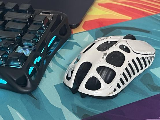 An organic styled computer mouse painted white, but scuffed back to bare material in many places with wear. It looks almost intentional but also very bad.