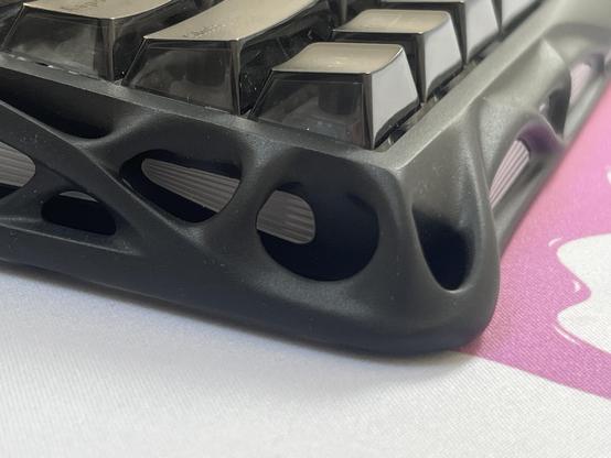 The edge of a mechanical keyboard showing an impossibly organic interconnecting web of curves.