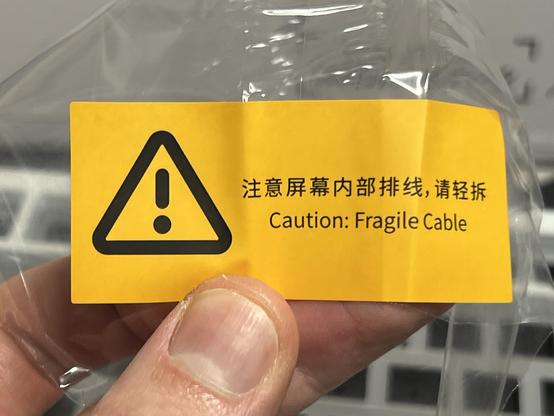 A bright yellow sticker with an exclamation warning sign reading “Caution: Fragile Cable.”