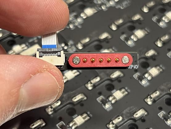 A tiny daughter PCB joining a flat flex connector to the corresponding magnetic plug for the receptacle in the keyboard base.