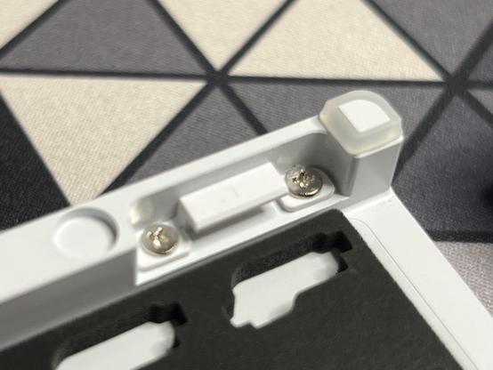 The white base of the keyboard with a recess into which a little plastic hook is screwed.
