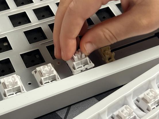 A tiny hand placing a mechanical keyboard switch.