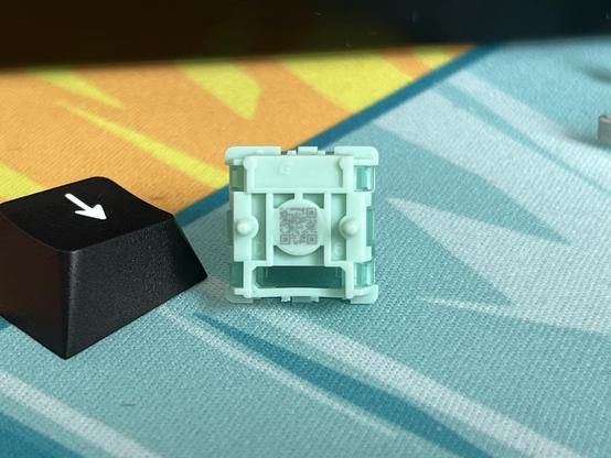 The bottom of a magnetic mechanical keyboard switch showing a tiny detailed QR code.