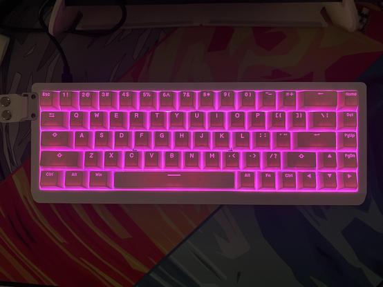 A white mech keyboard with white shine through switches lit up bright neon pink.