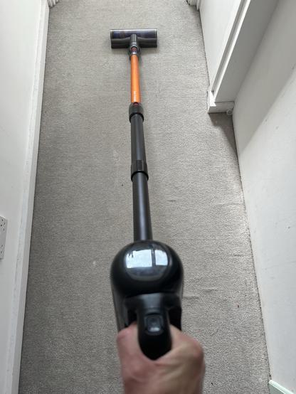 The handheld part of a Eufy E20 with the black extension tube connected. An orange Dyson V7 tube is connected to that and a Dyson hard floor brush at the end. It’s both electrically and mechanically compatible.