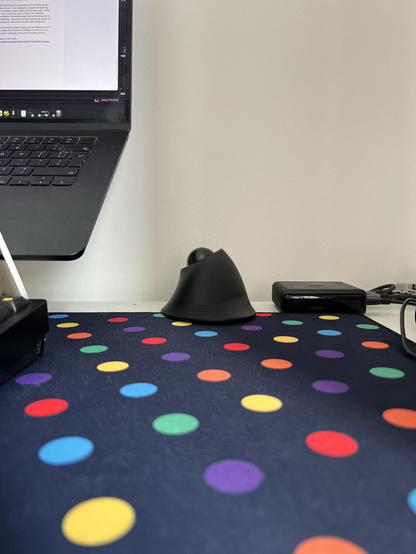 A ProtoArc wireless trackball mouse shoved right to the back edge of a desk, up against the wall.