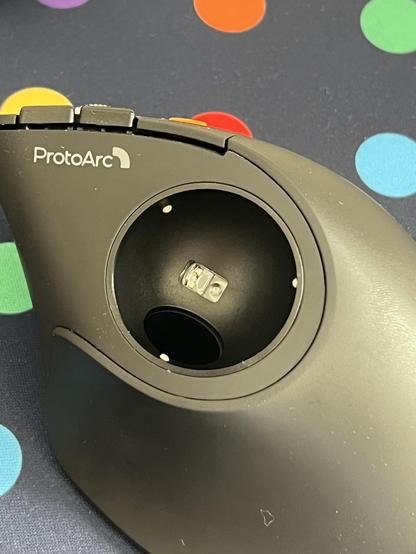 A view down into a trackball mouse with the ball removed. The sensor sits at the bottom of a ball-shaped recess, flanked by three little round dots that support the ball.