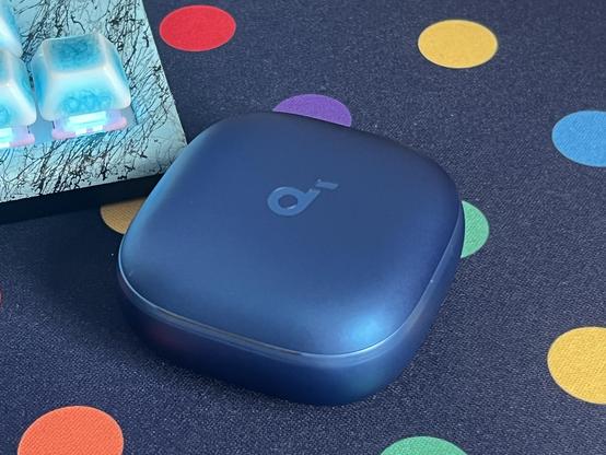A small bulbous blue earbuds case with a “d” logo on top.