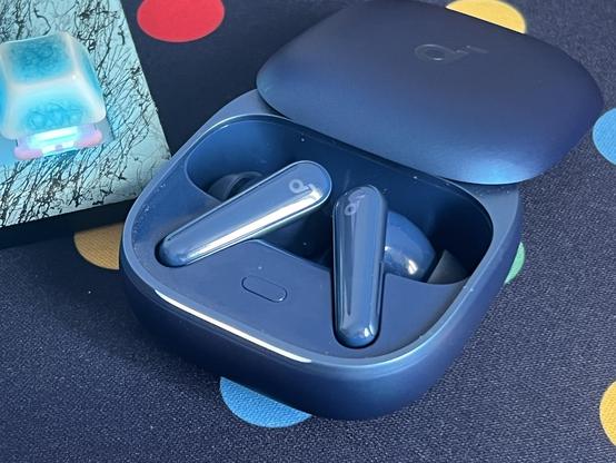 A small blue earbuds case open to show the earbuds inside.