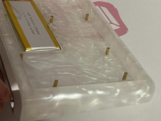 A weird milky resin keyboard base with a smattering of brass screw posts sticking up in the base.
