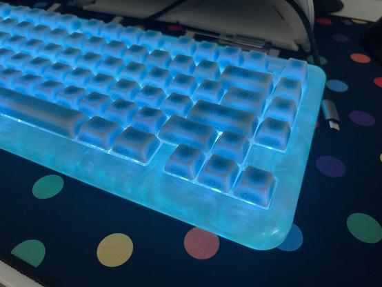 Ceramic crazed keycaps on a swirly resin keyboard all glowing blue.