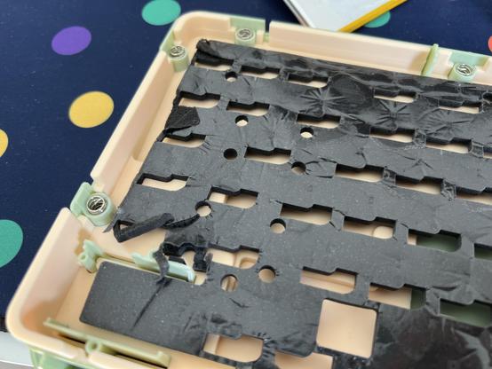 The PCB damping foam from a mechanical keyboard, peeled away from the PCB and torn into a wrinkled, ripped, useless mess.