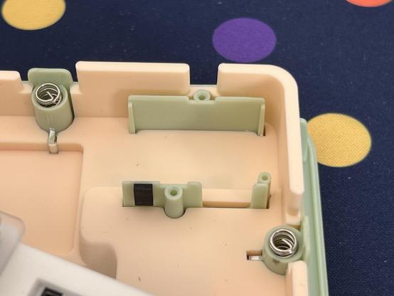 Plastic walls and screw posts inside the bottom of a mechanical keyboard case, unmistakably the size and shape you would expect to find an LCD module mounted to.