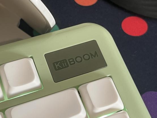 Closeup of a keyboard logo badge showing a KiiBOOM logo debossed and enamelled into the surface.