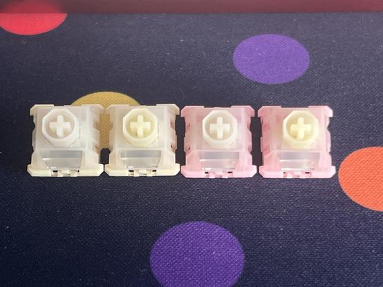 Four keyboard switches arranged in a line, the middle two are hybrid swaps of parts from the outer two, though the only visible difference is a slight change in colour of the stem.