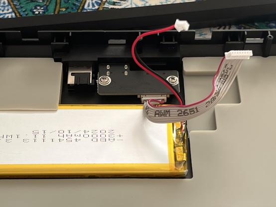 The bottom shell of a mechanical keyboard featuring a large chunk of silicone damping material and a LiPo battery nestled in it.