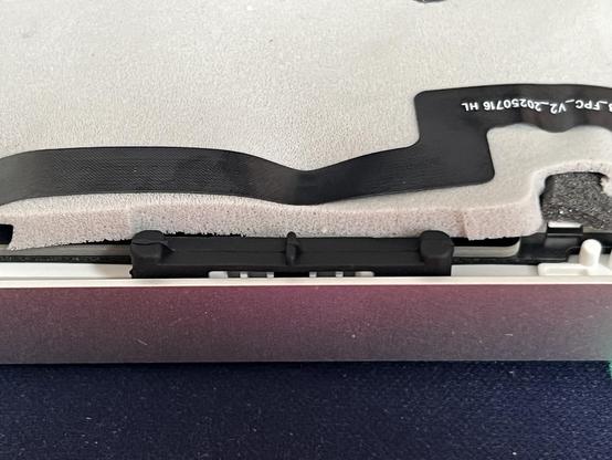 A black rubber cantilever style damper about an inch long, separating the keyboard plate and PCB assembly from the outer case while still retaining it.