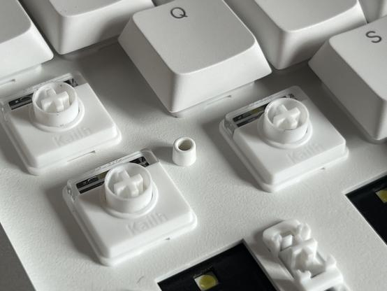 A textured white plastic switch plate with a couple of switches revealed and a little tunnel-like protrusion next to one of the switches.
