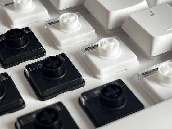 A mix of black and white low profile keyboard switches mounted into a white plate.