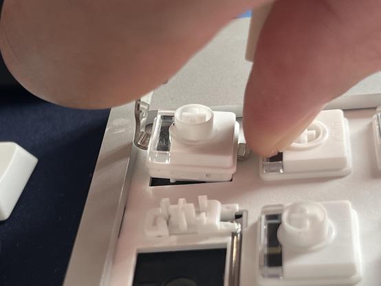 A white low profile keyboard switch being removed from a keyboard.