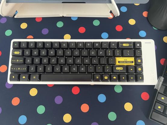 A low profile, compact, 65% mechanical keyboard populated with black and yellow Leica camera inspired keycaps.