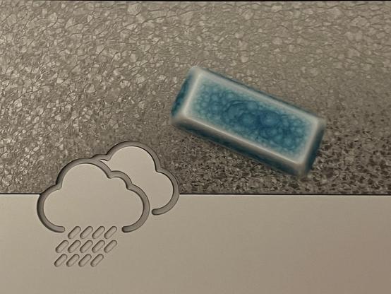 A single crazed blue ceramic keycap sat on the underside of the Rainy75, showing the similarity between its textured metal surface and the voronoi-like pattern on the keycap itself.