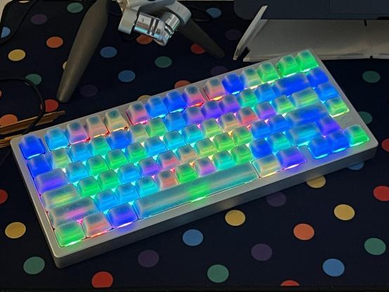A silver, 75% mechanical keyboard populated with crazed ceramic keycaps and backlit in a range of bright colours.