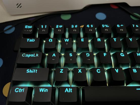 A closeup of a black mechanical keyboard showing illuminated shine through legends on the keycaps.