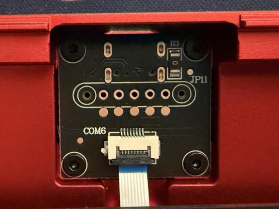 A small USB daughter board with a flat flex cable snaking down from it. A series of throughole .1” pitch pins and a distinct outline suggest a landing for a magnetic connector.