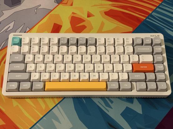 A white keyboard with predominately grey and white keycaps, Esc, Spacebar and Enter are picked out in teal, yellow and orange respectively.