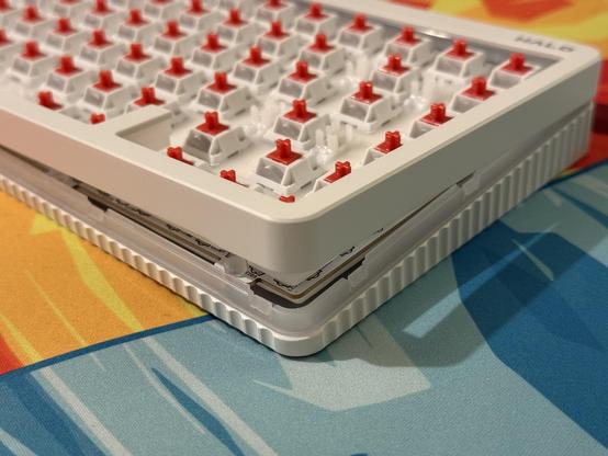 A white mechanical keyboard with all the keycaps removed. It’s pried apart in the corner, but there’s still some prying to do.