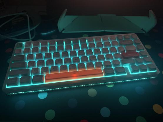 A white mechanical keyboard lit up bright teal. There’s a little light bleed through an orange spacebar, but the backlight is otherwise very nice, very uniform, very bright.
