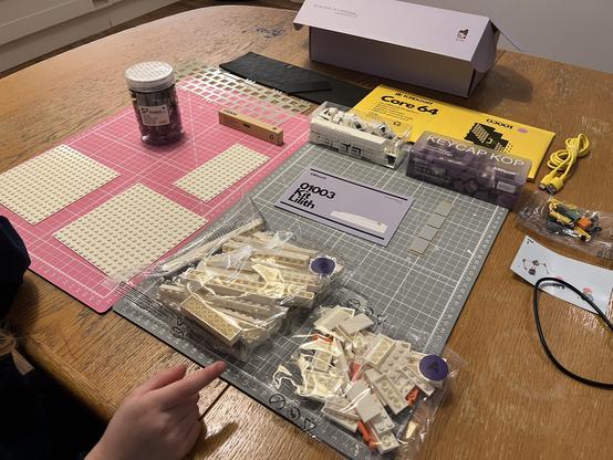 All of the pieces of the keyboard removed from the box and laid out upon two cutting mats on a kitchen table.