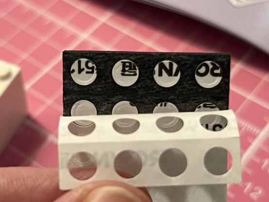 The backing from a foam pad peeling away from the pre-cut holes, still stuck inside the pad. They are deceptively difficult to remove.